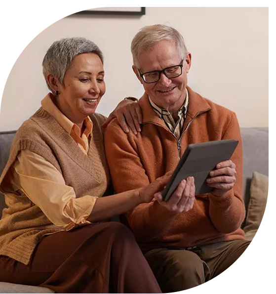 A man and woman sitting on the couch looking at an ipad.