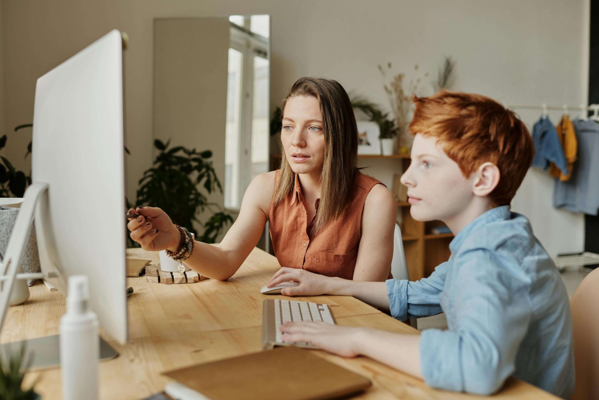 A woman and boy sitting at a table with a computer.