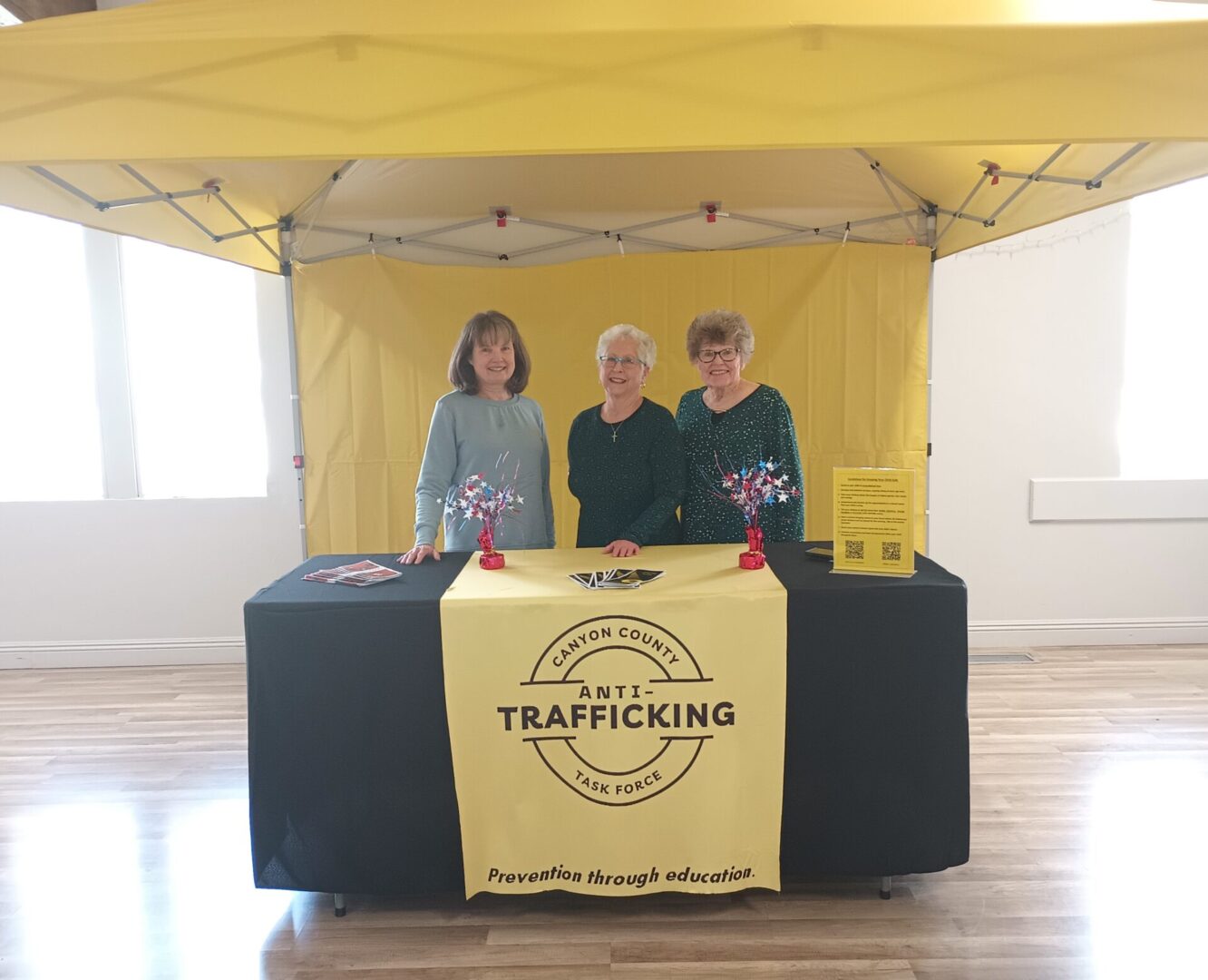 Three people standing in front of a yellow tent.