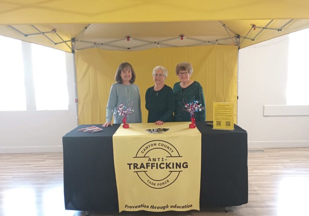 Three people standing in front of a yellow tent.